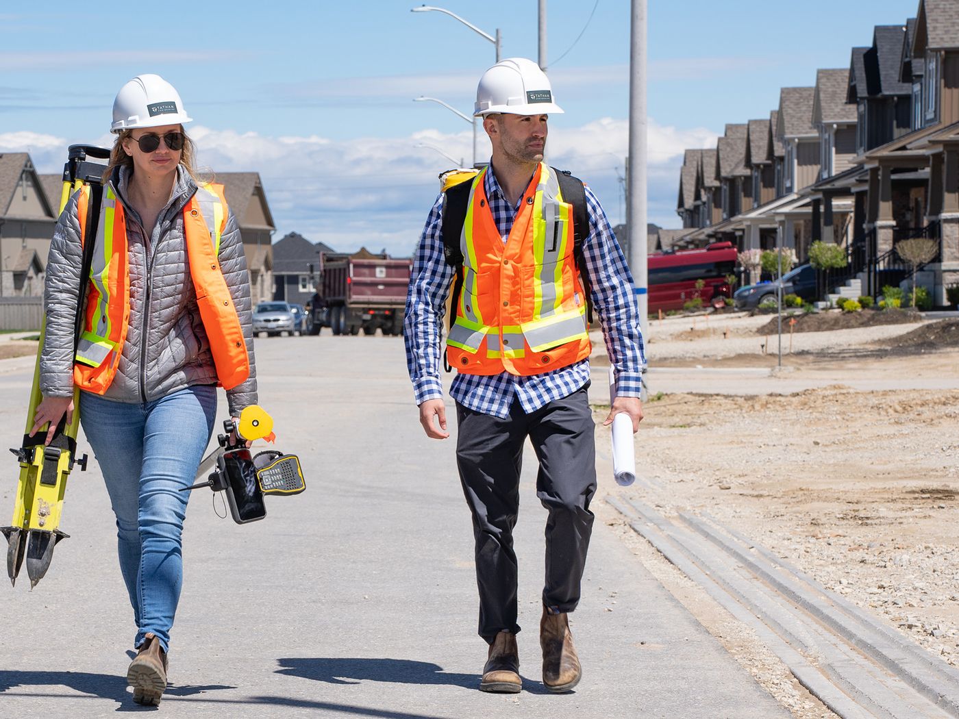 Two Tatham staff carrying survey equipment on a construction site